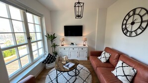 Een woonkamer met een bank, salontafel en een tv aan de muur.