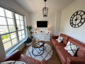 Ein Wohnzimmer mit einer Couch, einem Couchtisch und einem an der Wand befestigten Fernseher.