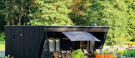 Una casa moderna de un solo piso, de color negro, con terraza y zona de estar al aire libre.
