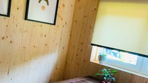 Een houten interieur met een tafel, stoelen, een hanglamp en een raam met een plant.