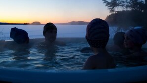 Lämminvesiallas, jossa on tilaa kolmelle henkilölle, ja sen ympärillä luonnonkaunista maisemaa sekä auringonlasku.