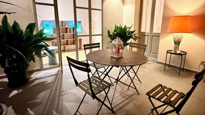Comedor con una mesa redonda, cuatro sillas, dos macetas y una lámpara de pared.