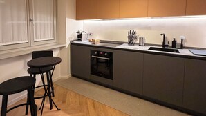 Una cocina moderna con horno empotrado, un lavamanos y una zona de comedor con taburetes.