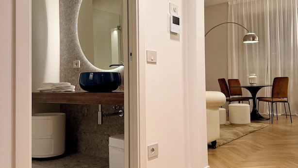 Un baño moderno con un espejo redondo, un lavamanos azul y un perchero para toallas.