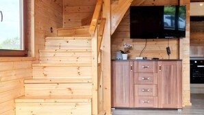 En inredning med träpanel, en trappa, träskåp och en platt-TV som är monterad på väggen.
