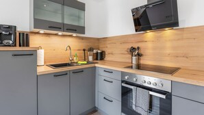 Een moderne keuken met grijze kastjes, een houten aanrechtblad, een roestvrijstalen spoelbak en een ingebouwde oven.