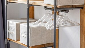 Een metalen rek met opbergdozen en witte kledinghangers.