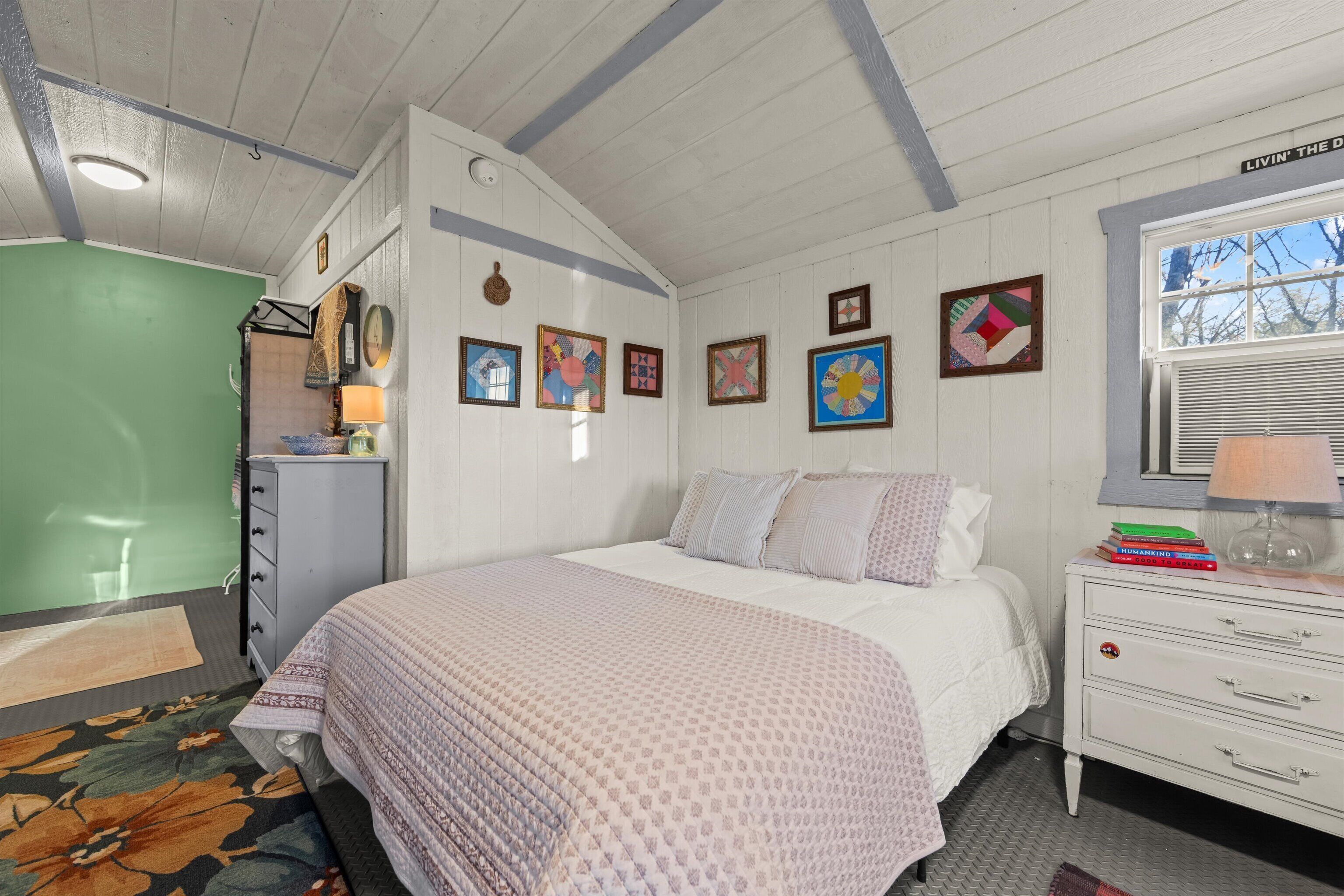 Un dormitorio con cama, cómoda y decoración en la pared.