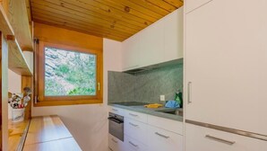 Eine kleine Küche mit weißen Schränken, einer Granit Arbeitsplatte und einem Fenster mit Blick auf Grünflächen.