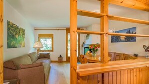 Ein gemütliches Wohnzimmer mit einer Holzbank, einem Sofa und einem Esstisch mit Blumen in einer Vase.