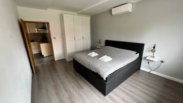 A bedroom with a bed, a wardrobe, a bedside table, and an air conditioning unit.