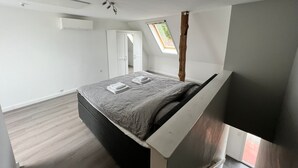 A bedroom with a bed, a skylight, a wardrobe, and a wooden beam. - mit privat Hottub und Klima. by Interhome (Neubörger)