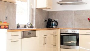 A modern kitchen with white cabinets, a built-in oven, and a stainless steel range hood. - mit privat Hottub und Klima. by Interhome (Neubörger)