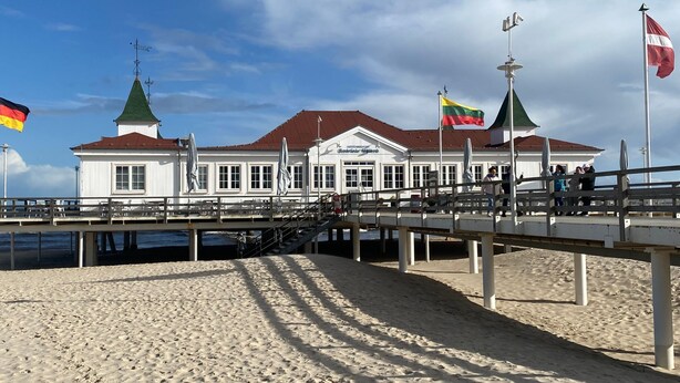 A coastal building with a white facade, a green roof, and a flagpole with multiple flags. - Haus Goodewind by Interhome (Ahlbeck)