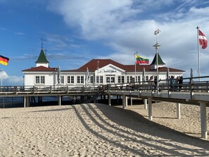 A coastal building with a white facade, a green roof, and a flagpole with multiple flags. - Haus Goodewind by Interhome (Ahlbeck)