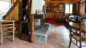 A rustic interior with a stone fireplace, wooden shelves, and a cozy seating area.