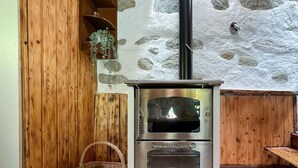 A wood-burning stove with a stone wall and wooden paneling.