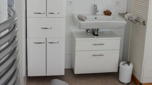 A modern bathroom with a white vanity, a mirror, a sink, and a toilet.