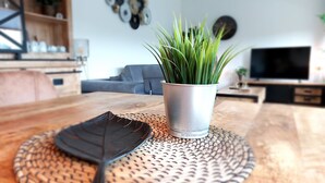 Uma mesa de jantar com um descanso trançado e um arranjo decorativo de folhas.