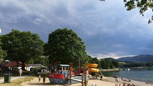 A beach with a playground, including slides and swings, near a lake with boats. - Top Ferienwohnung am Diemelsee, Sauerland Nähe Willingen Winterberg by Interhome (Diemelsee)