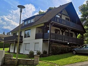 Une maison à deux étages avec un balcon, un garage et une pelouse bien entretenue.