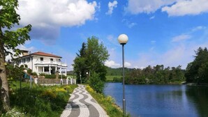 A paved pathway beside a lake, a white building with a red roof, and a street lamp. - Top Ferienwohnung am Diemelsee, Sauerland Nähe Willingen Winterberg by Interhome (Diemelsee)