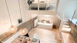 A modern interior with a dining area, a sofa, and a staircase.