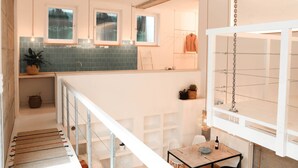 A modern kitchen with a central island, a dining area with a table and chairs, and a staircase leading to an upper level.