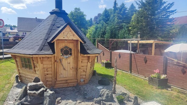 A small wooden cabin with a hexagonal door and a chimney.