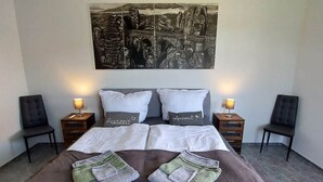 A hotel room with a large bed, two bedside tables, two chairs, and a wall-mounted artwork.