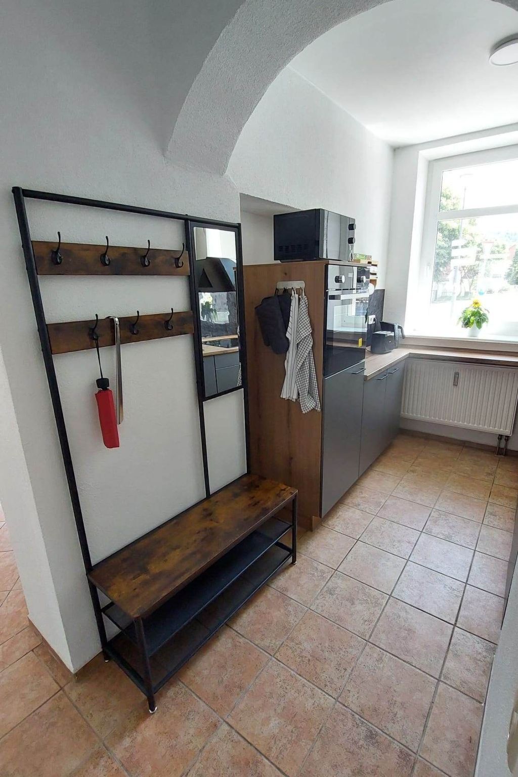 Una cocina con un banco empotrado, un estante con ganchos y un ventanal que proporciona luz natural.