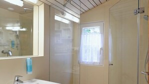 A bathroom with a white sink, a mirror, and a shower area. - Berg Hütte Hochpillberg by Interhome (Pill)