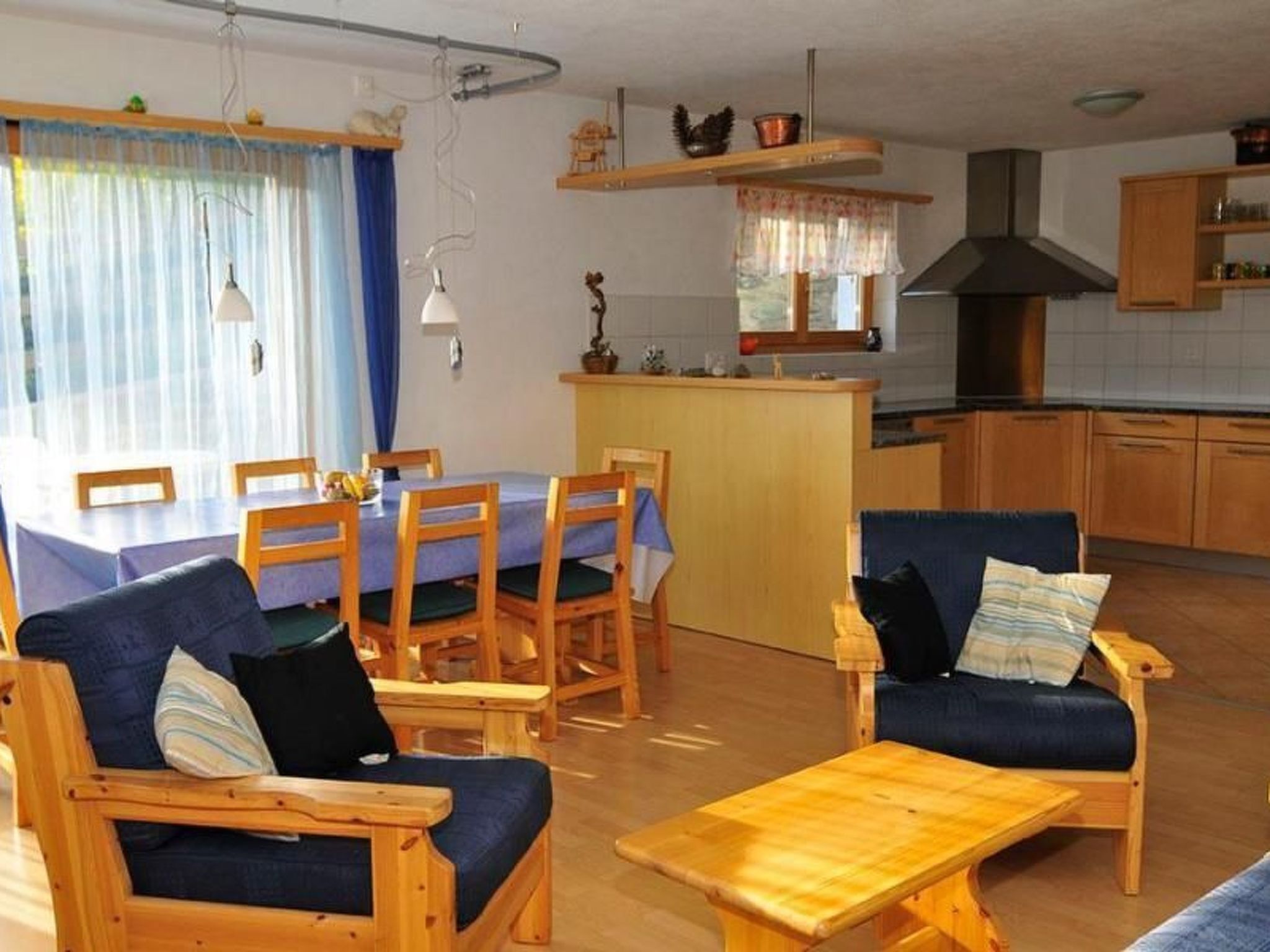 Ein gemütliches Wohnzimmer mit Essbereich, Holzmöbeln und einer Küche im Hintergrund.