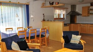 Ein gemütliches Wohnzimmer mit Essbereich, Holzmöbeln und einer Küche im Hintergrund.
