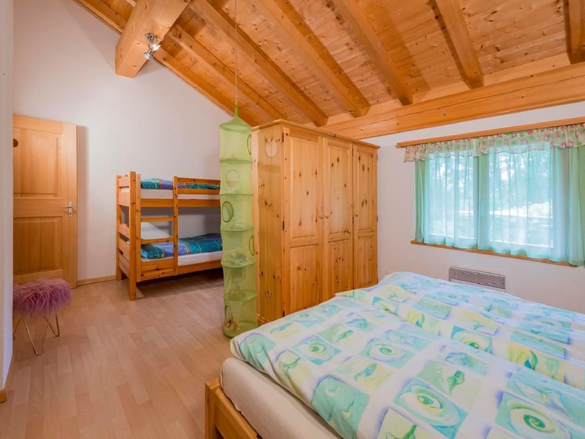 Ein Schlafzimmer mit einem Etagenbett, einem Kleiderschrank und einem großen Bett mit einem gemusterten Überwurf.
