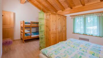Ein Schlafzimmer mit einem Etagenbett, einem Kleiderschrank und einem großen Bett mit einem gemusterten Überwurf.