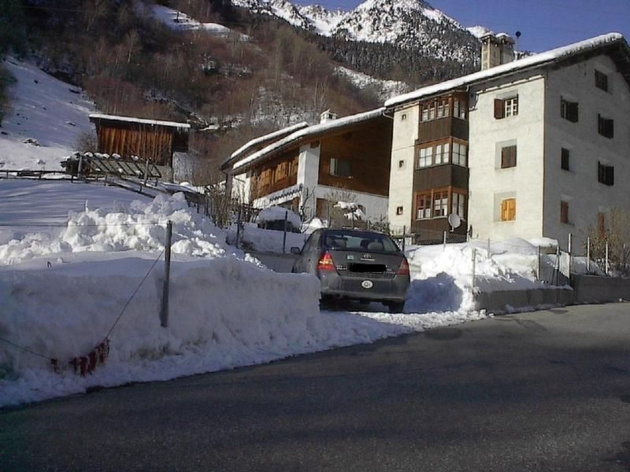 Un bâtiment doté d’un toit en pente, une voiture garée devant et un paysage enneigé.