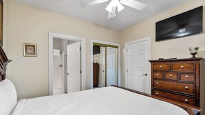 Una camera da letto con un letto grande, una cassettiera in legno e una ventola a soffitto.