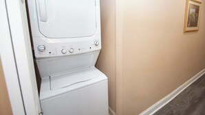 A laundry room with stacked washers and dryers, beige walls, and a framed picture on the wall. - World Tour 104-202a (Myrtle Beach)