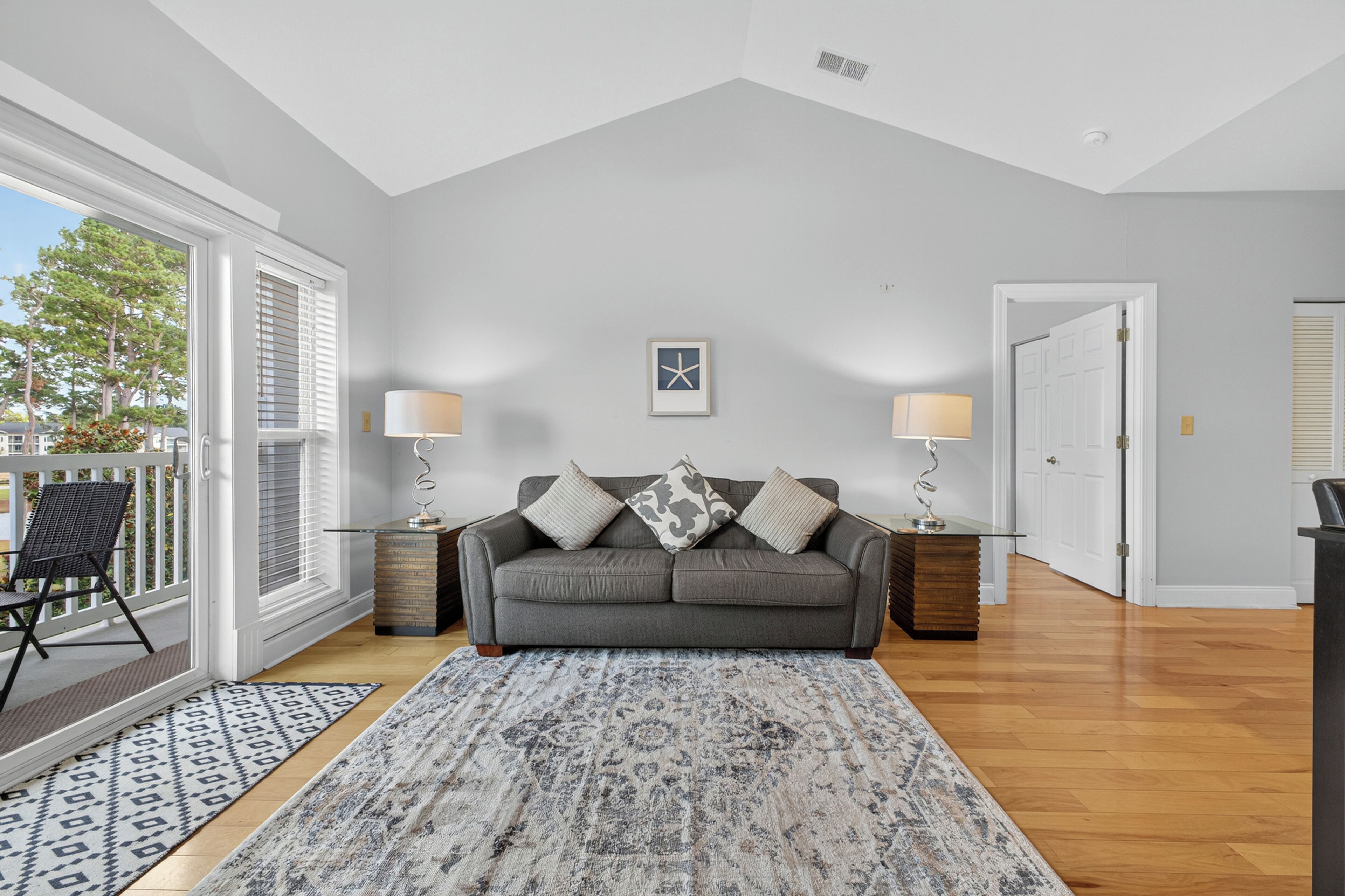 A living room with a grey sofa, patterned rug, and two lamps.
