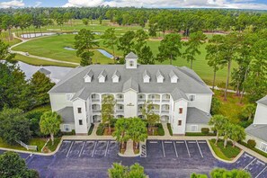 A multi-story hotel with a central courtyard, surrounded by lush greenery and a golf course. - World Tour 1009-302 (Myrtle Beach)