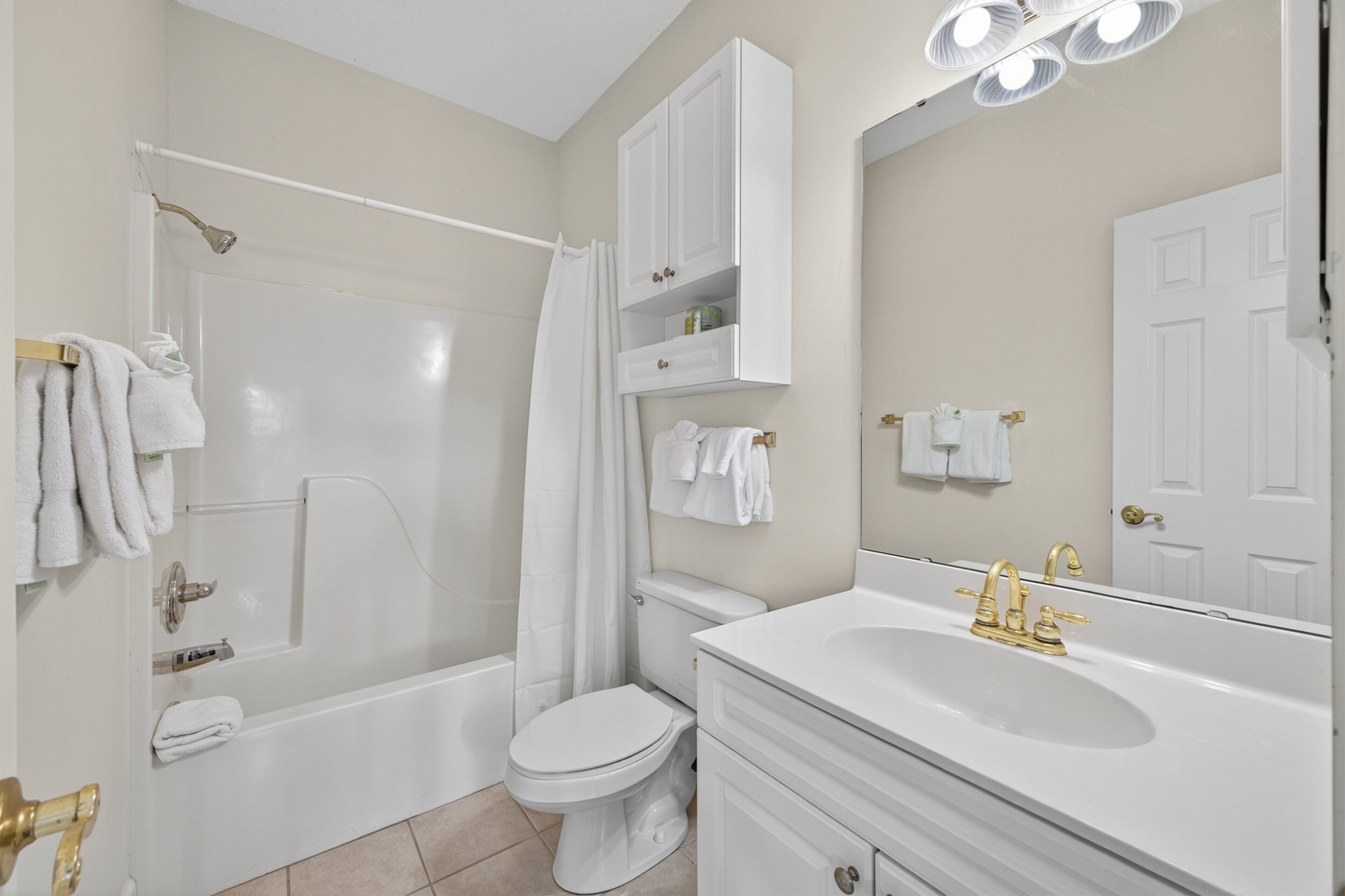 A bathroom with a bathtub, toilet, sink, and a mirror.