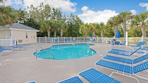 A pool area with blue lounge chairs and a white fence. - Magnolia Place 4765-303 (Myrtle Beach)