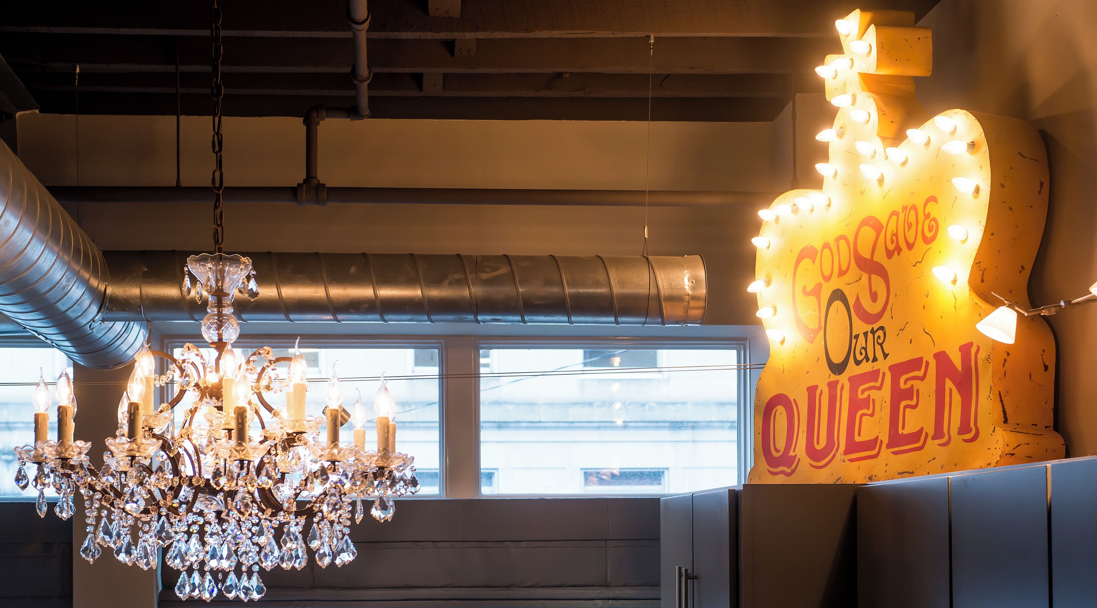 A chandelier with crystal decorations and a sign with lights on a wall.