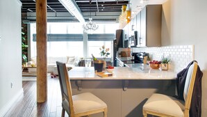 Una cucina moderna con un piano di lavoro in marmo, sedie in legno e un'ampia finestra.