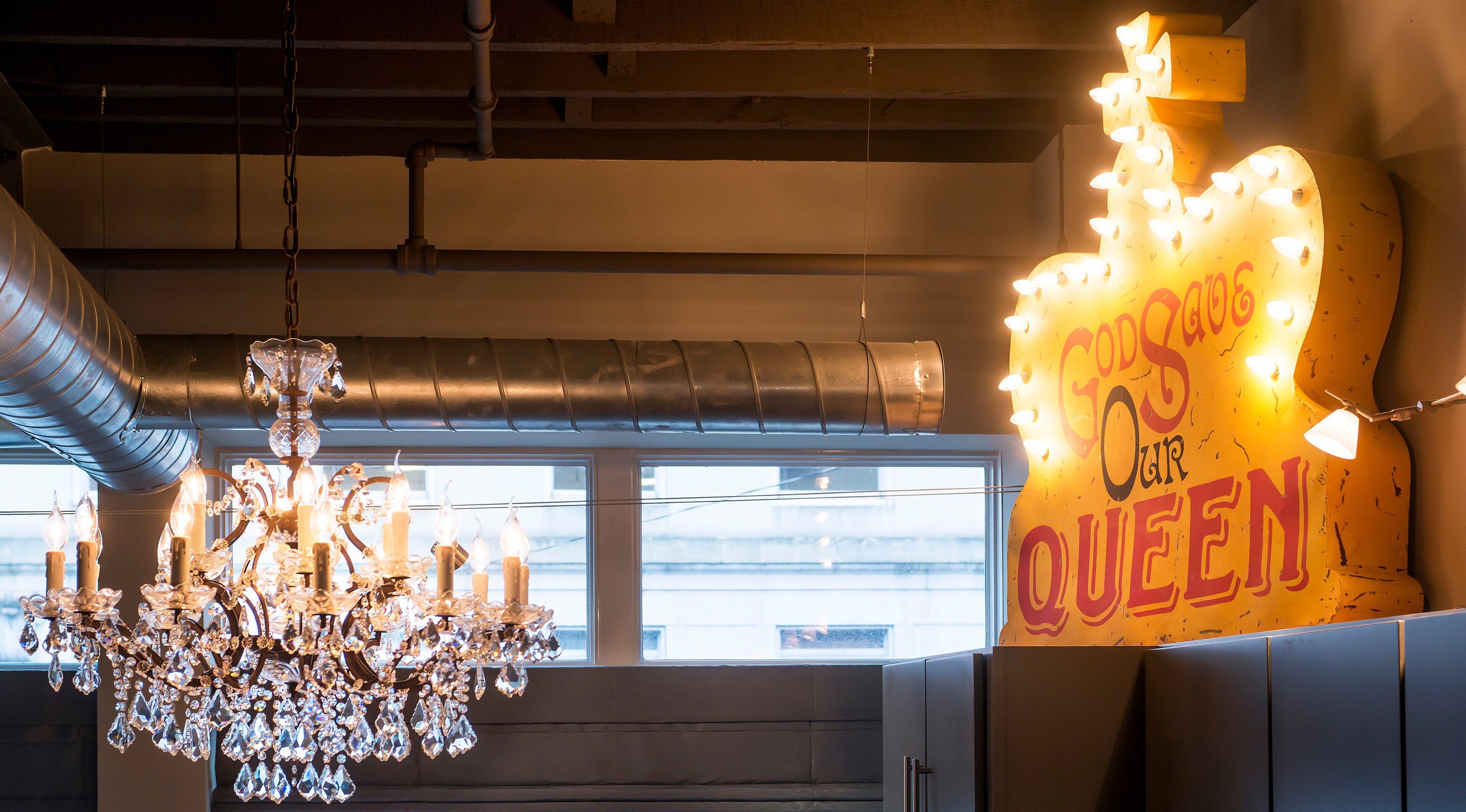A chandelier with crystal decorations and a neon sign that reads "God's Own Queen".