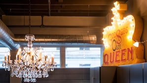 Un lampadario con decorazioni in cristallo e un neon con su scritto 'God's Own Queen'.
