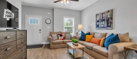 A living room with a sofa set, a coffee table, a TV, and a ceiling fan.