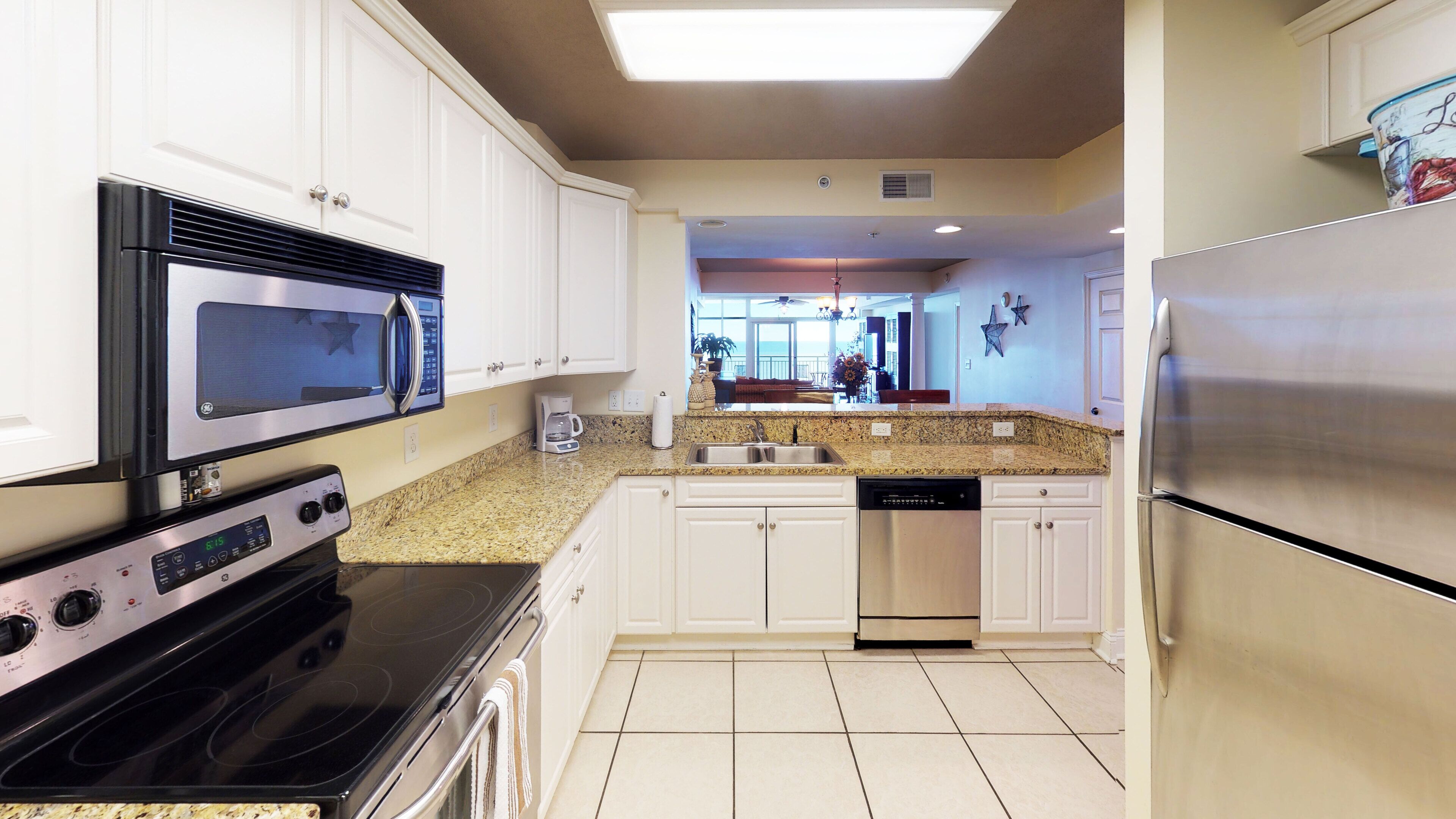 A modern kitchen with white cabinets, stainless steel appliances, a granite countertop, and a dishwasher.