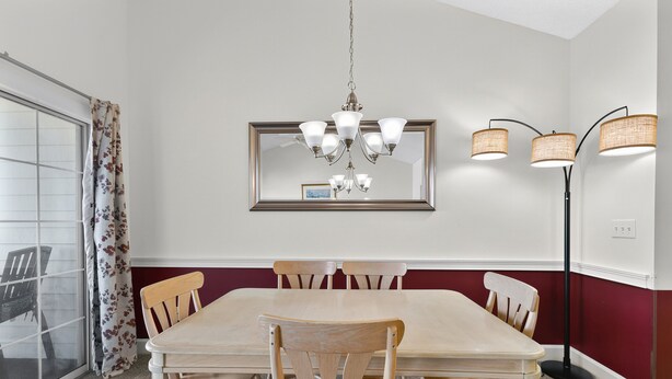 A dining area with a table and chairs, a chandelier, a mirror, and a floor lamp. - Magnolia Place 4677-302 (Myrtle Beach)